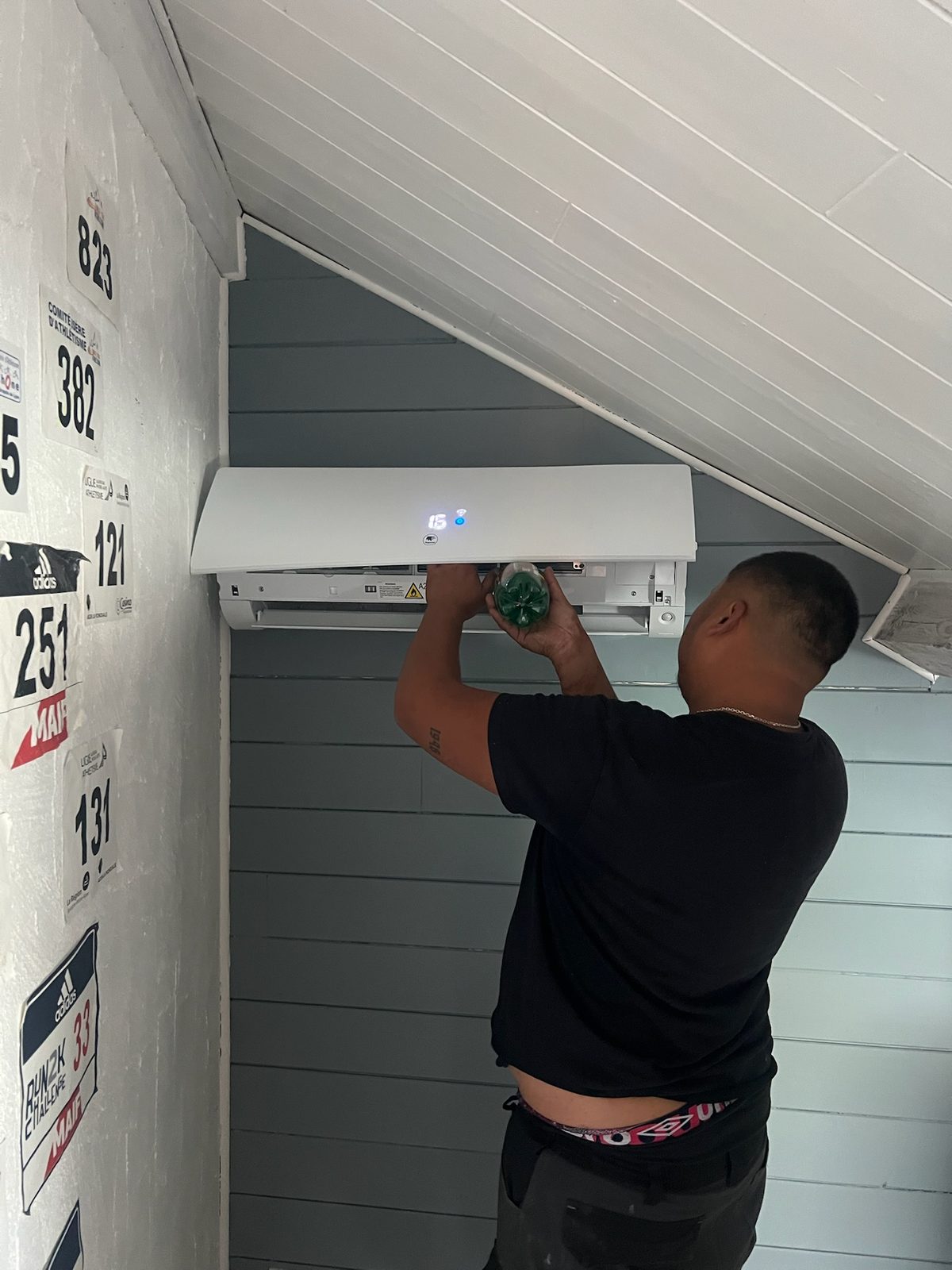 Technicien de Confort Habitat posant une unité intérieure de climatisation